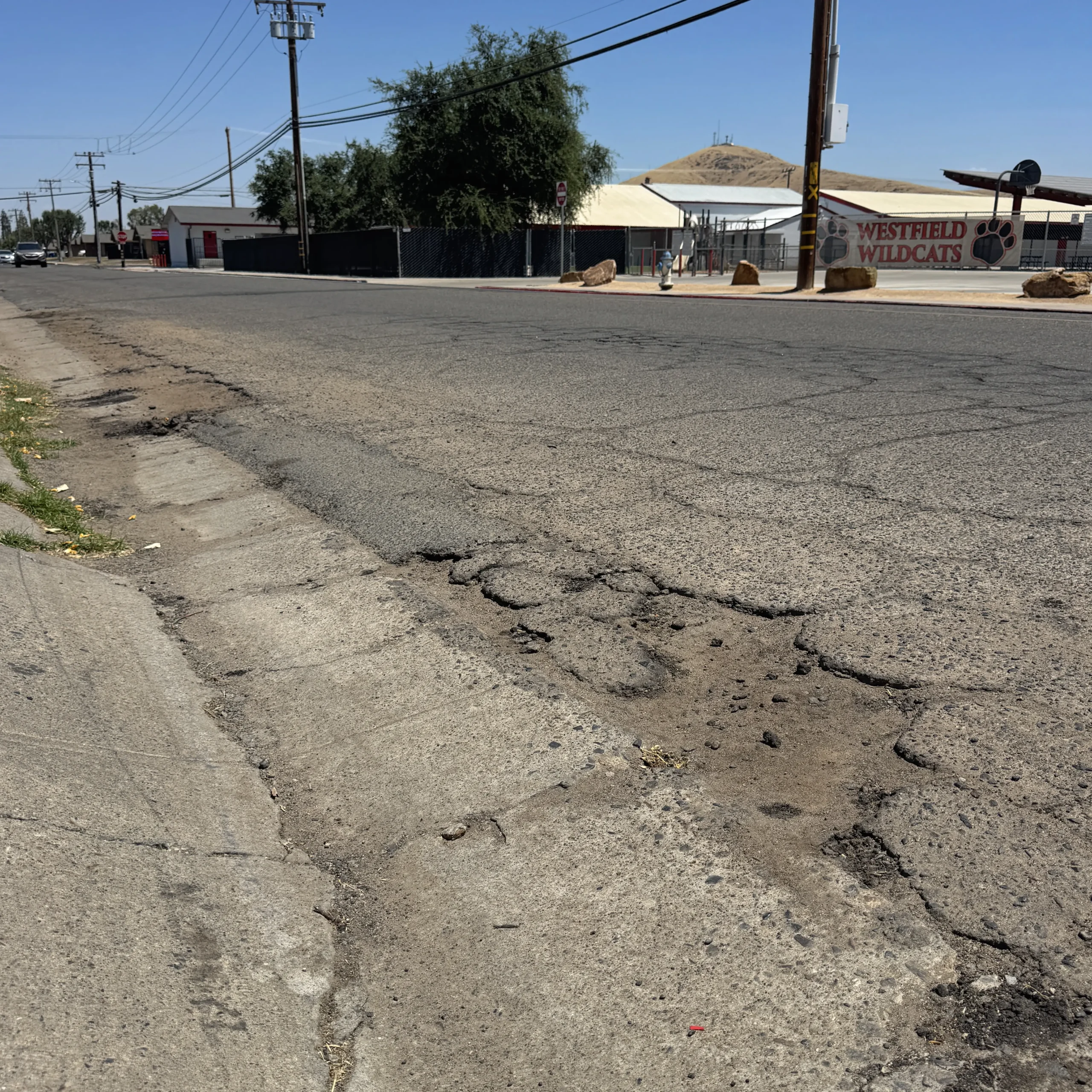 Deteriorating neighborhood street with cracked pavement and road damage in Porterville.
