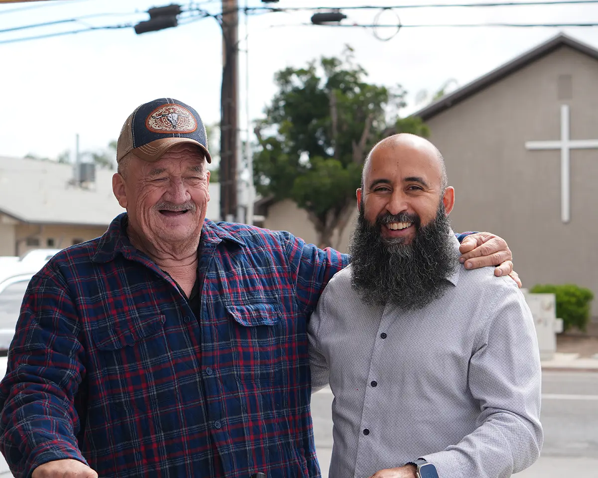 Taha Saleh smiling alongside a local resident